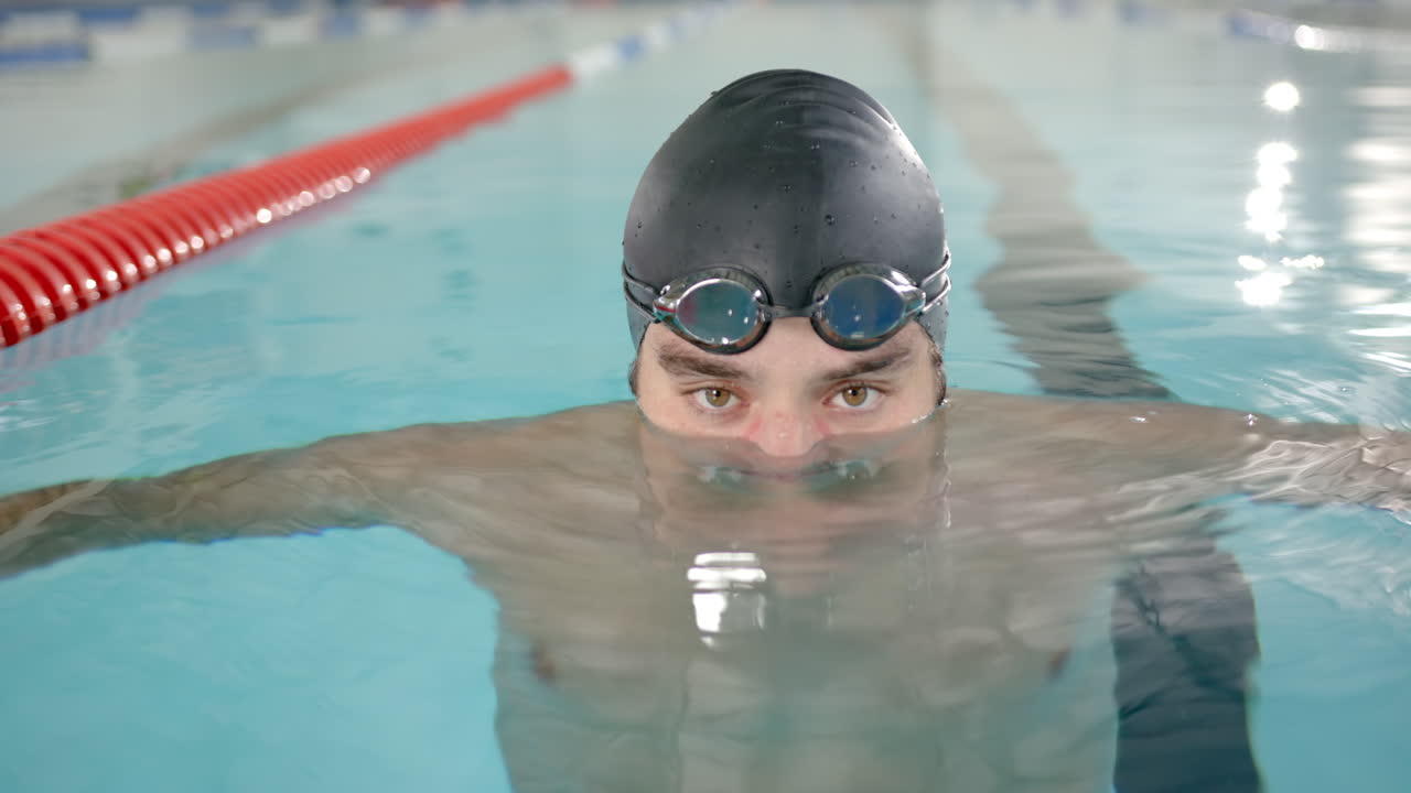 male female swimmer in pool wearing swim cap and goggles, preparing for competition