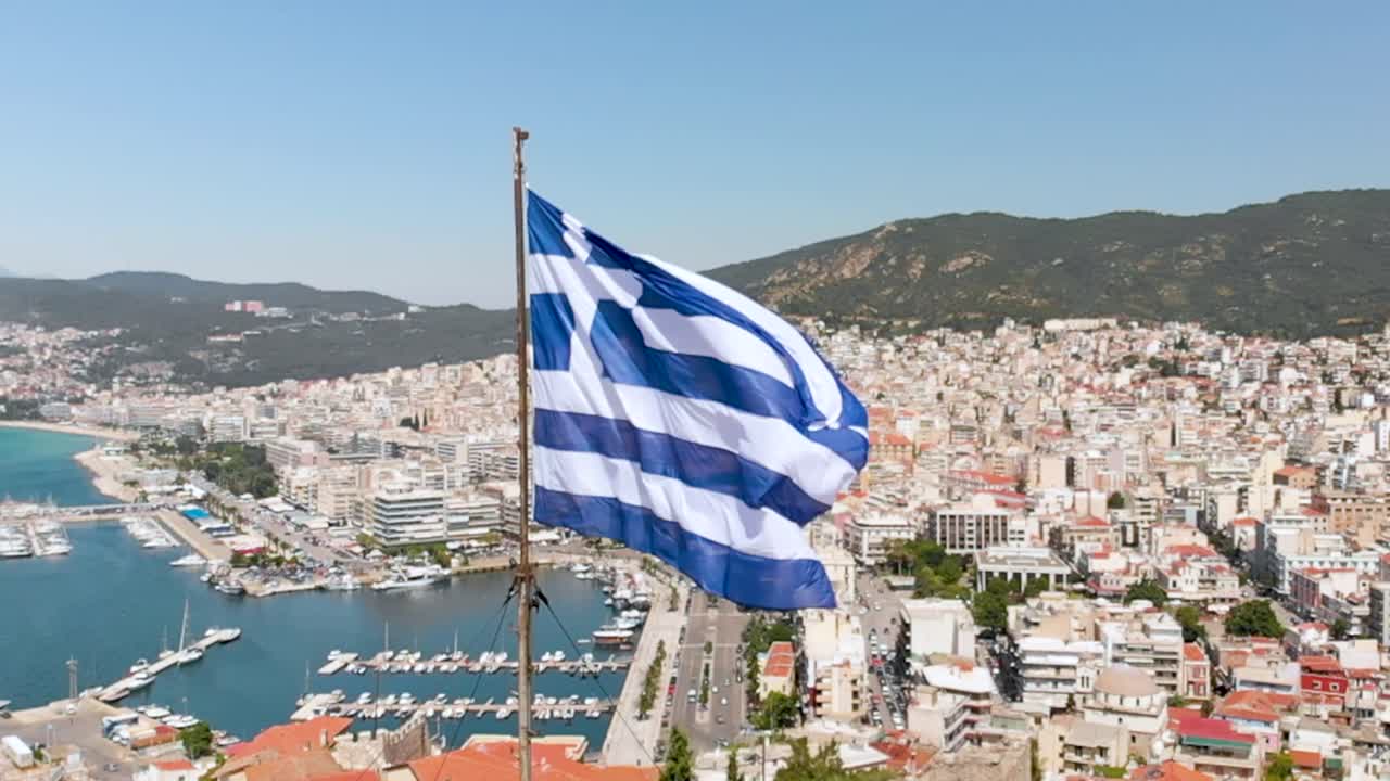 bandera griega ondeando en la torre fortaleza de kavala ciudad vieja grecia, vídeo aéreo en cámara lenta