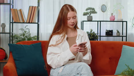 girl sitting on sofa using smartphone share messages on social media application watching movies