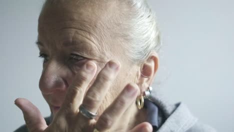 slow motion portrait elder senior woman applies herself white cream make up wrinkles ageing concept