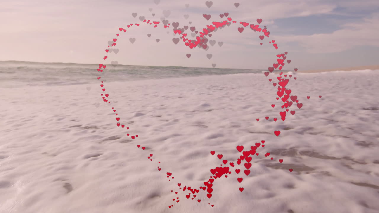 Heart-shaped animation of red and pink hearts over ocean waves on beach
