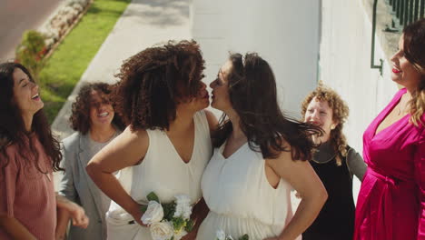 female couple kissing under thrown rice after wedding ceremony