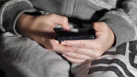 The-boy-is-looking-at-the-phone-while-lying-on-the-bed