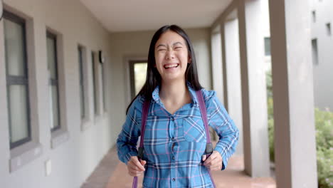 teenage asian girl with a joyful expression stands in a school corridor in high school