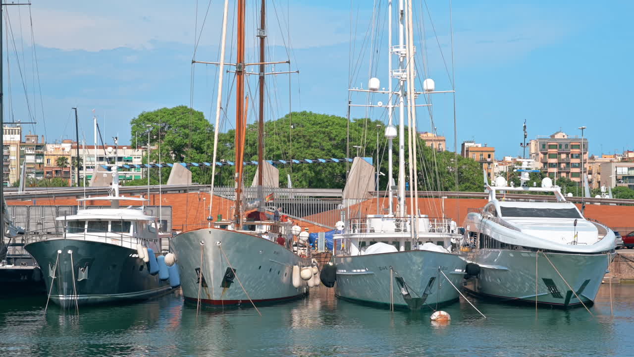 Sea port in Barcelona, Spain. Multiple moored yachts, sunny weather, buildings on the background