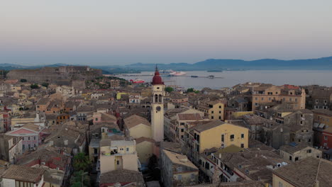 slow orbit drone video of saint spyridon church in corfu old town at dawn, with swallows flying across the early morning sky