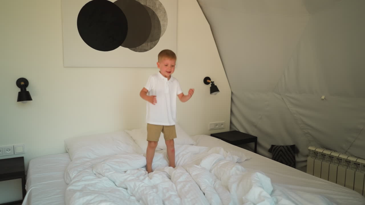 럭셔리 캠핑에서 침대 위에 높이 뛰어다니는 아이, 멋진 침실에서 부드러운 매트리스에서 즐거운 소년, 거대한 호텔 텐트에서 즐거운 아이