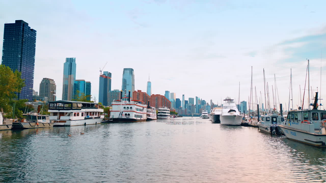 Jersey City, USA, 1 July 2025: Moving by the narrow river along the numerous boats at berths. Sailing and boating in Jersey City. Manhattan scenery at backdrop