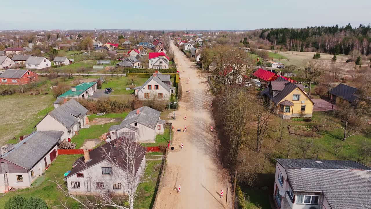 Private homes line a dusty road as construction signals spring renewal