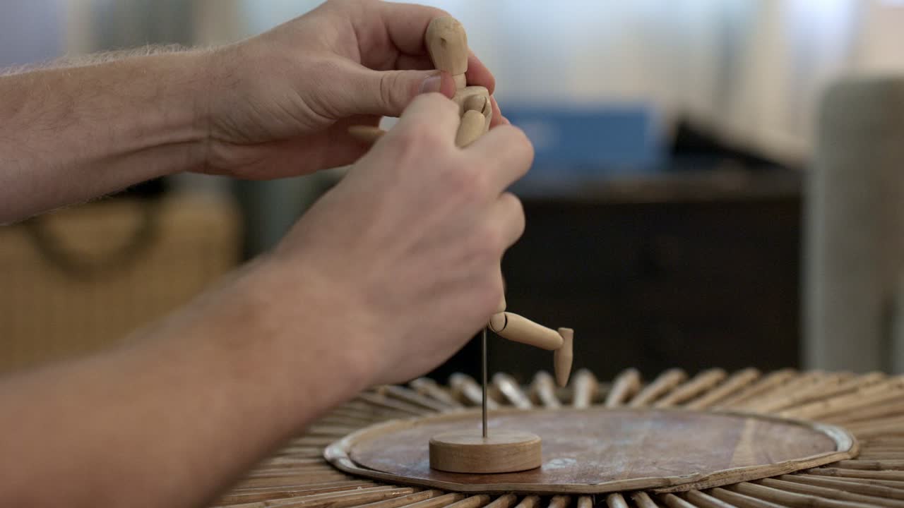 Wooden Artists' Mannequin for art being adjusted by male hands