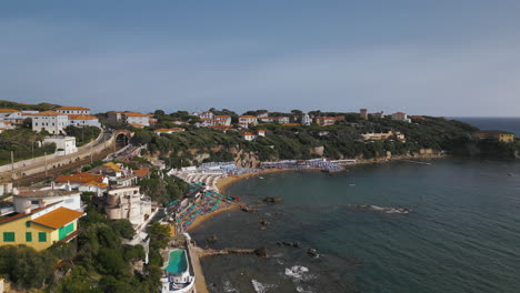 italy tuscan beach coastline homes as waves roll into bay, drone