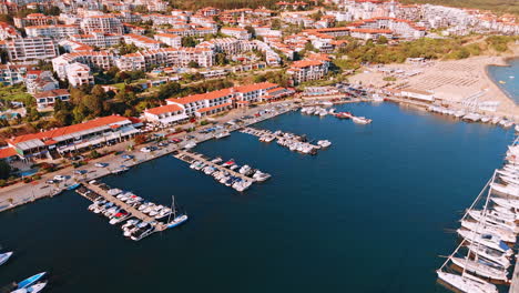 Multiple boats and jet ski scooters at the berths near the sandy beach. Drone footage at the sunny resort Sveti Vlas, Bulgaria