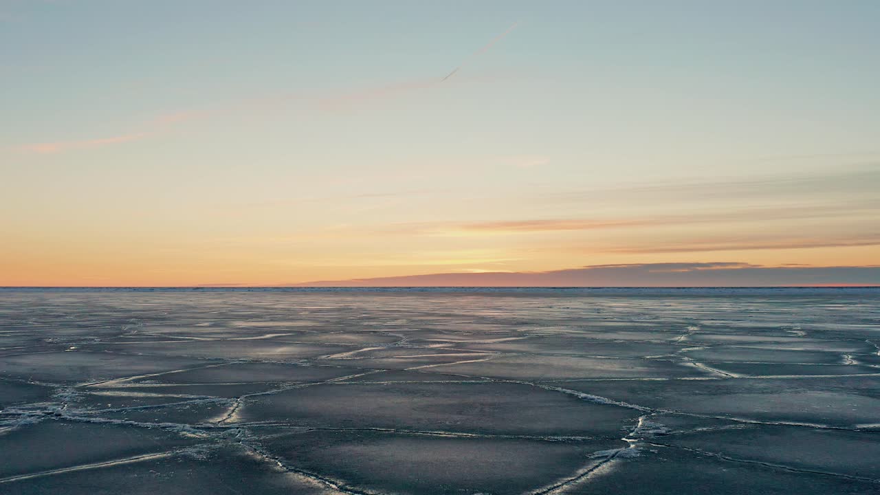 겨울 동안 발트해 연안에서 눈에 보이는 금이 간 얼음 조각과 물의 큰 들판 위로 천천히 뒤로 이동합니다.