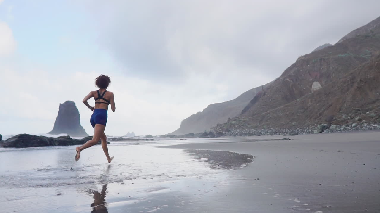 Morning Marvel: Athletic Woman's Sculpting Run Along the Ocean in Slow Motion
