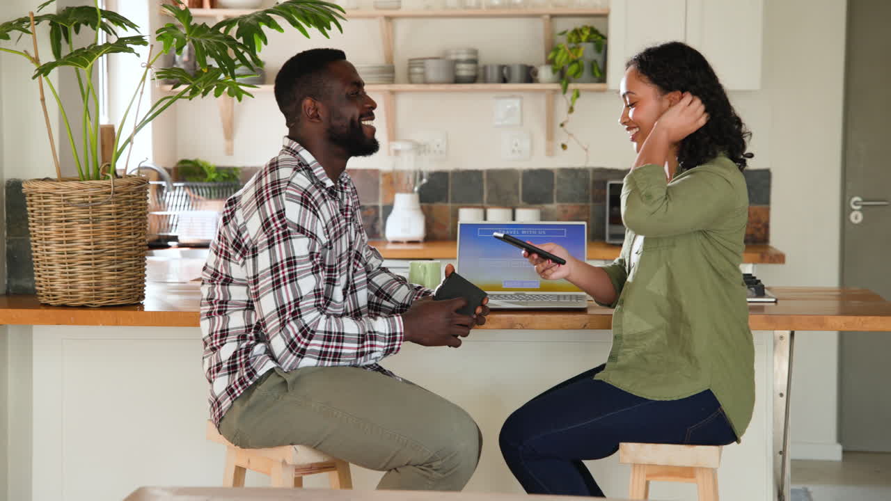 multiracial couple planning travel at home using laptop and smartphone