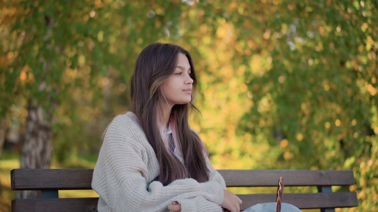 Giovane donna seduta su una panchina del parco in autunno