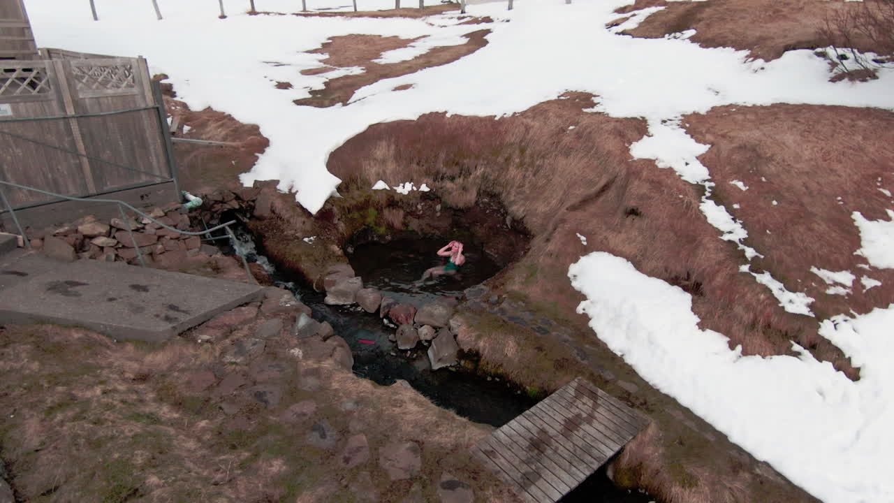 Woman in swimming suit laying in natural hot spring in Iceland