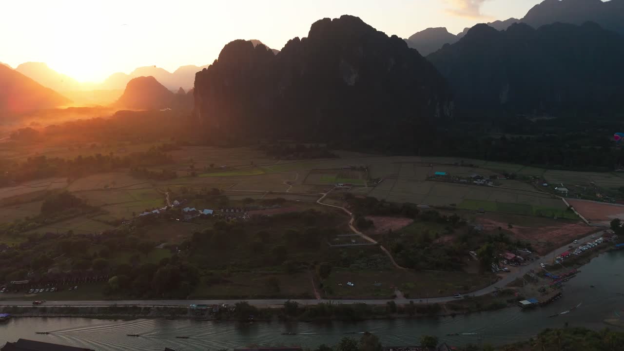 Aerial fly above Vang Vieng town in Laos at sunset over Nam Song River