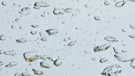 Burbujas-De-Aire-Subiendo-El-Primer-Plano-De-La-Superficie-Del-Agua.-Líquido-Mineral-Burbujeante-A-La-Luz.