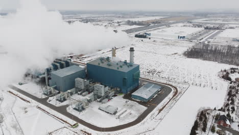 una instalación industrial en invierno, grandes columnas de vapor, paisaje cubierto de nieve, vista aérea