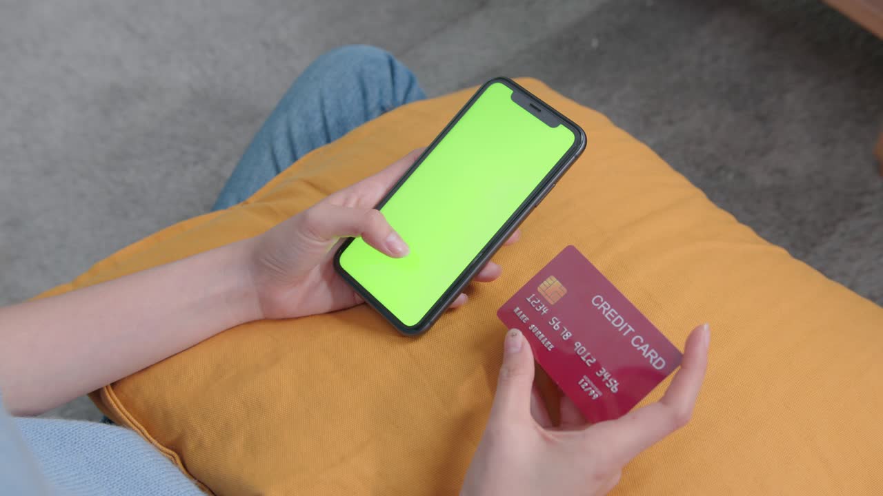 Woman holding mockup smartphone green screen and credit card with paying for shopping online.