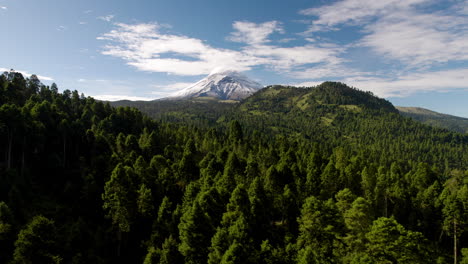 drone shot showing the snowy top of the popocatepetl volcano in mexico city and the lush forests that surround it