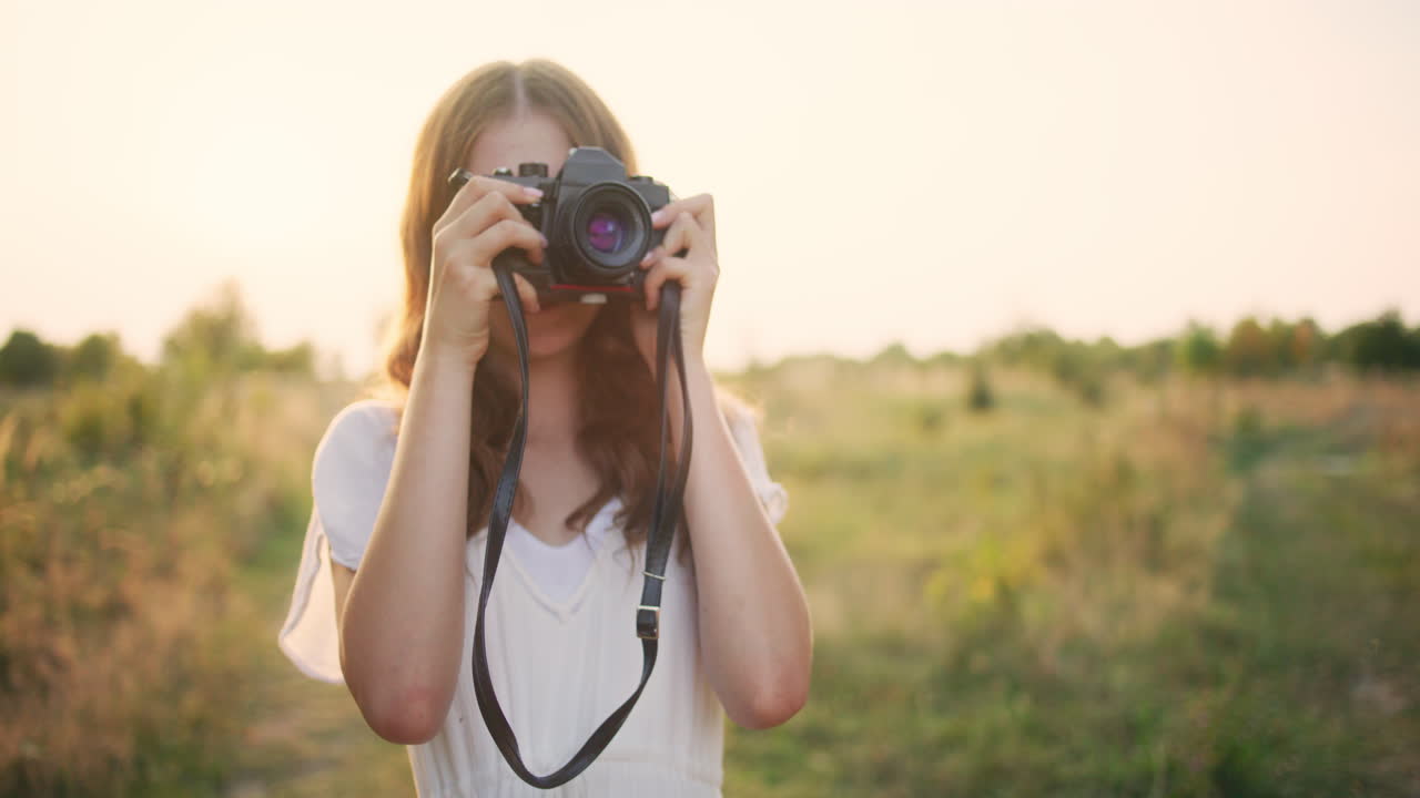 Girl with vintage camera in the meadow
