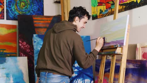 trabalhando no estúdio criativo do pintor jovem artista de raça mista pinta um quadro