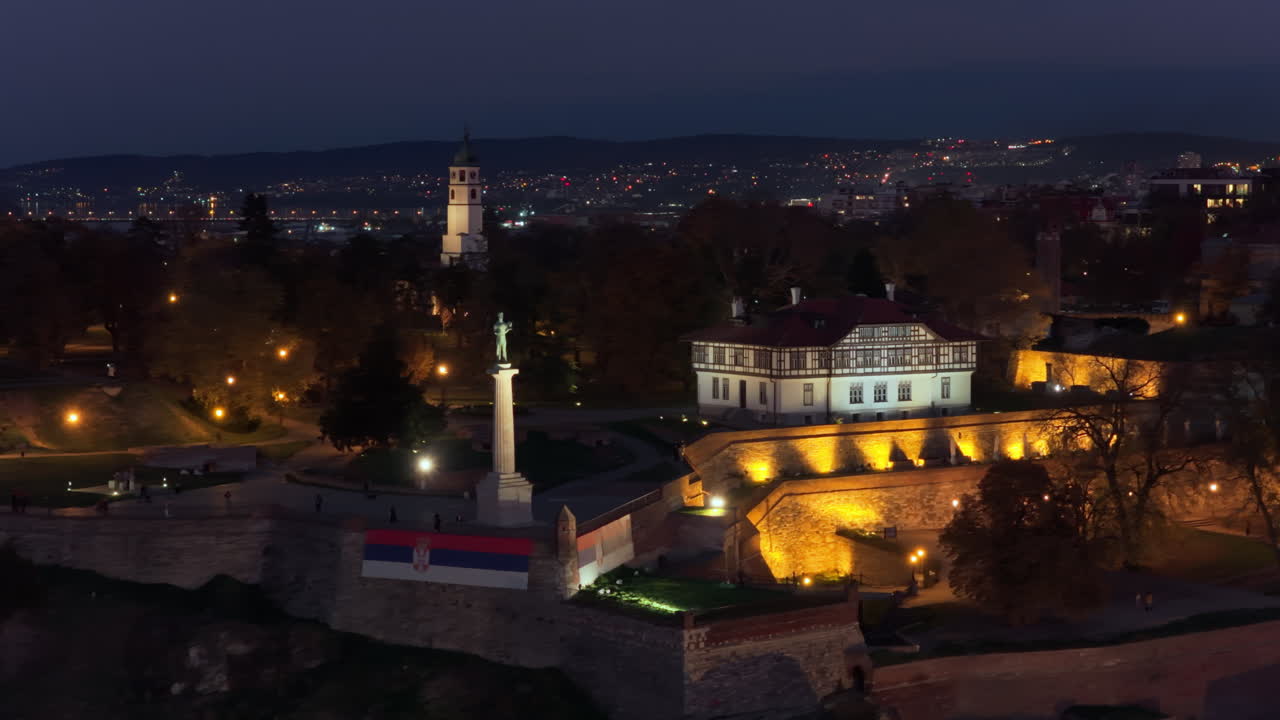 Aerial drone view of Belgrade's iconic Victor Monument, beautifully lit against the fortress and old architecture at night
