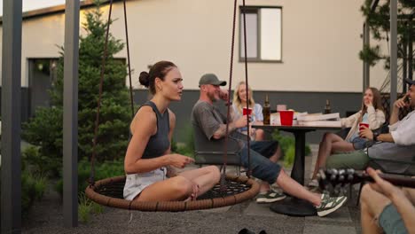 Happy-brunette-girl-sings-a-song-while-her-boyfriend-plays-the-guitar-during-a-party-during-the-day-in-the-backyard-of-a-country-house