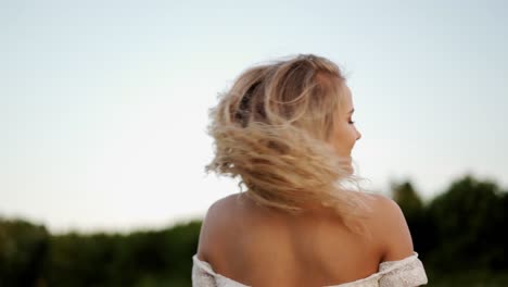 una chica rubia bonita sonriendo mientras se gira durante la puesta de sol de la hora dorada