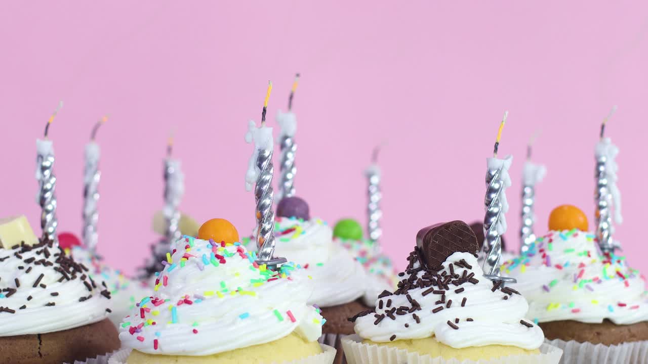 Blowing birthday candles on cup cakes with cream for birthday party