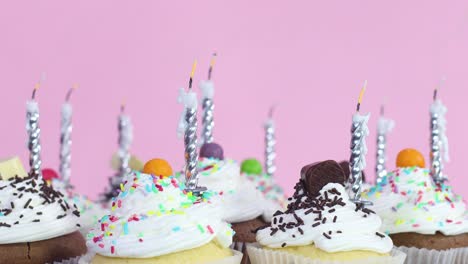 blowing birthday candles on cup cakes with cream for birthday party
