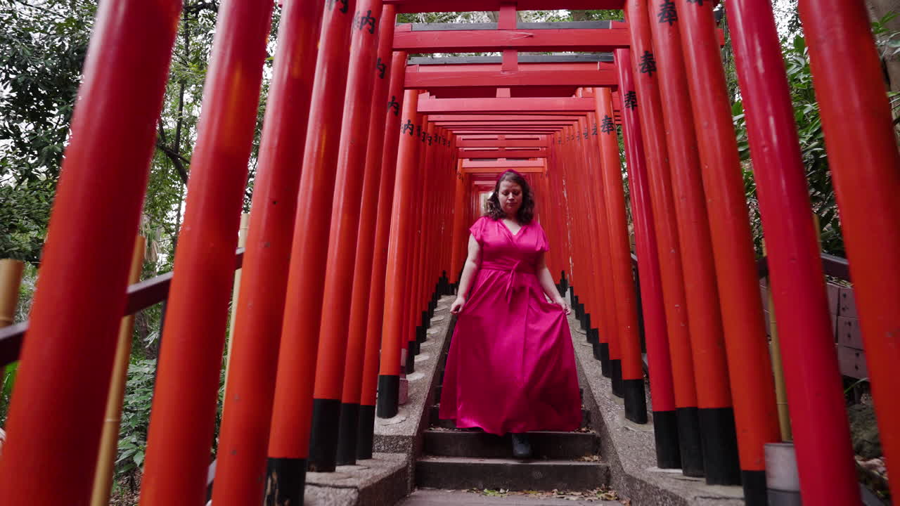 Woman In Red Dress Walking Down Through Torii Gates At Hie Shrine In Tokyo, Japan. pullback tracking shot