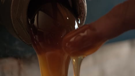 macro disparo sobre la miel que fluye por un tubo, en un dedo