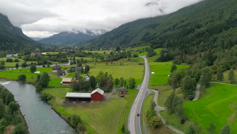 aerial forward dolly zoom shot of car driving next to the river and through the beautiful landscaping in stryn norway