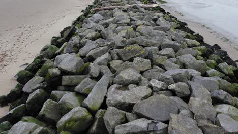 aerial: close up dolly over tidal sea defence, llanelli, 4k drone