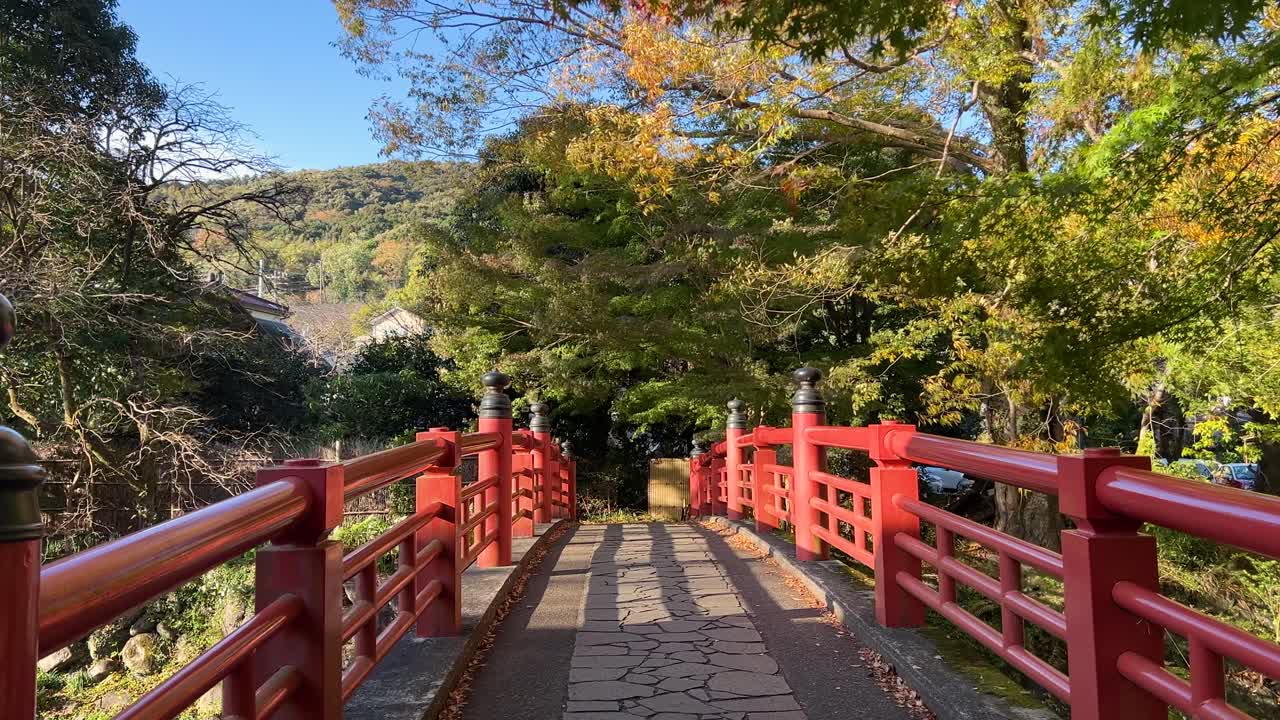 pov caminando sobre el típico puente rojo en shuzenji con colores de otoño
