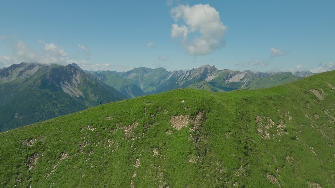 A lush green mountain landscape under a bright blue sky, captured in the Austrian Alps