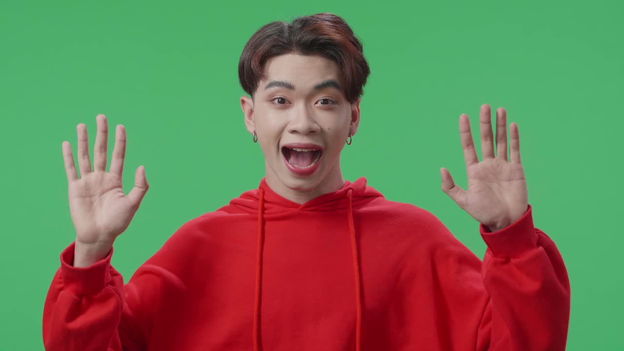 Portrait Of A Young Asian Transgender Male Opening Her Eyes With Palms And Becoming Surprised In The Green Screen Studio