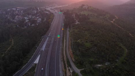 aerial view of a highway winding through forested hills at sunset