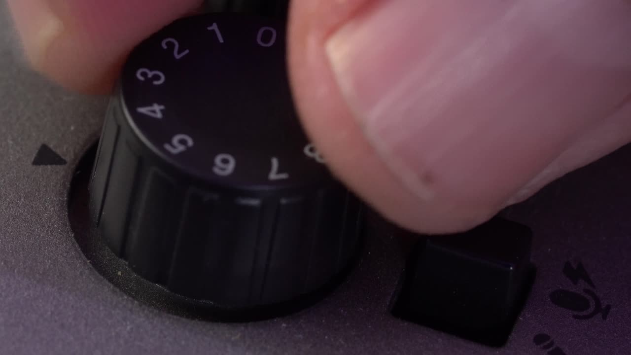 Close up of a hand adjusting a volume knob on audio equipment, showing tactile interaction and detail