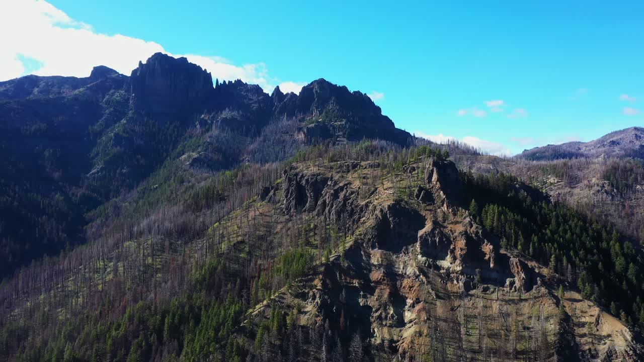 Aerial scenic backwards shot revealing the pacific northwest landscapes with rugged mountains and forest in Washington State.