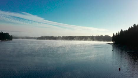 Lake-fog-steam-rises-in-early-morning-across-mystical-alpine-forest-lake-in-early-morning