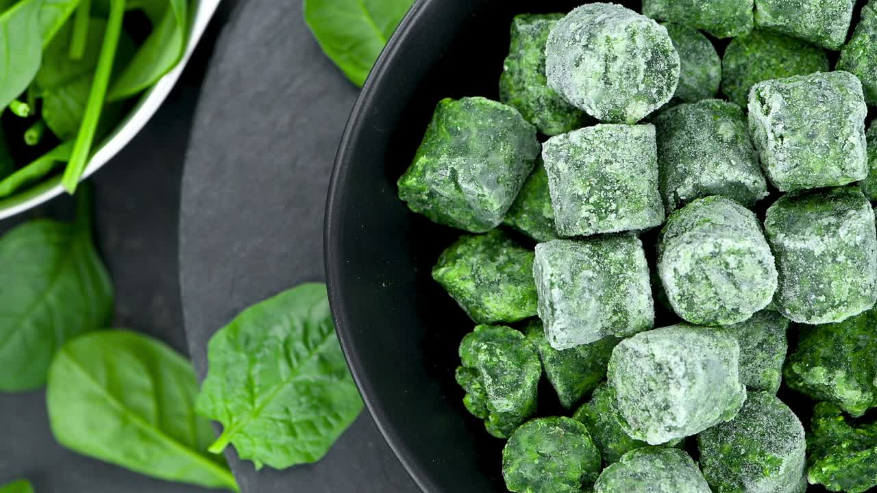 cubos de espinaca congelados en una placa giratoria (con un bucle sin costuras)