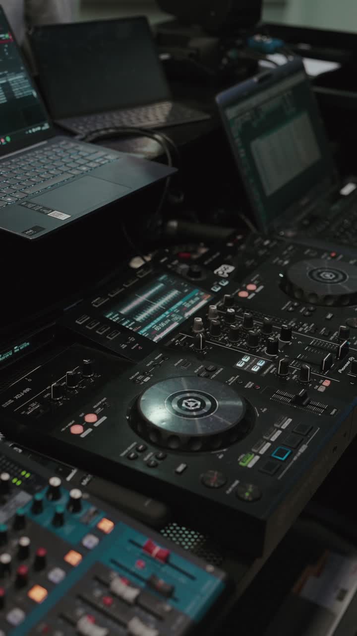 DJ controller mixer with laptops and audio controls on table indoors