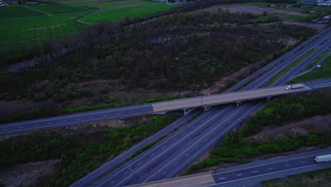 A-serene-twilight-scene-captures-trucks-and-cars-traveling-across-highway-surrounded-by-lush-green-fields-in-Pennsylvania