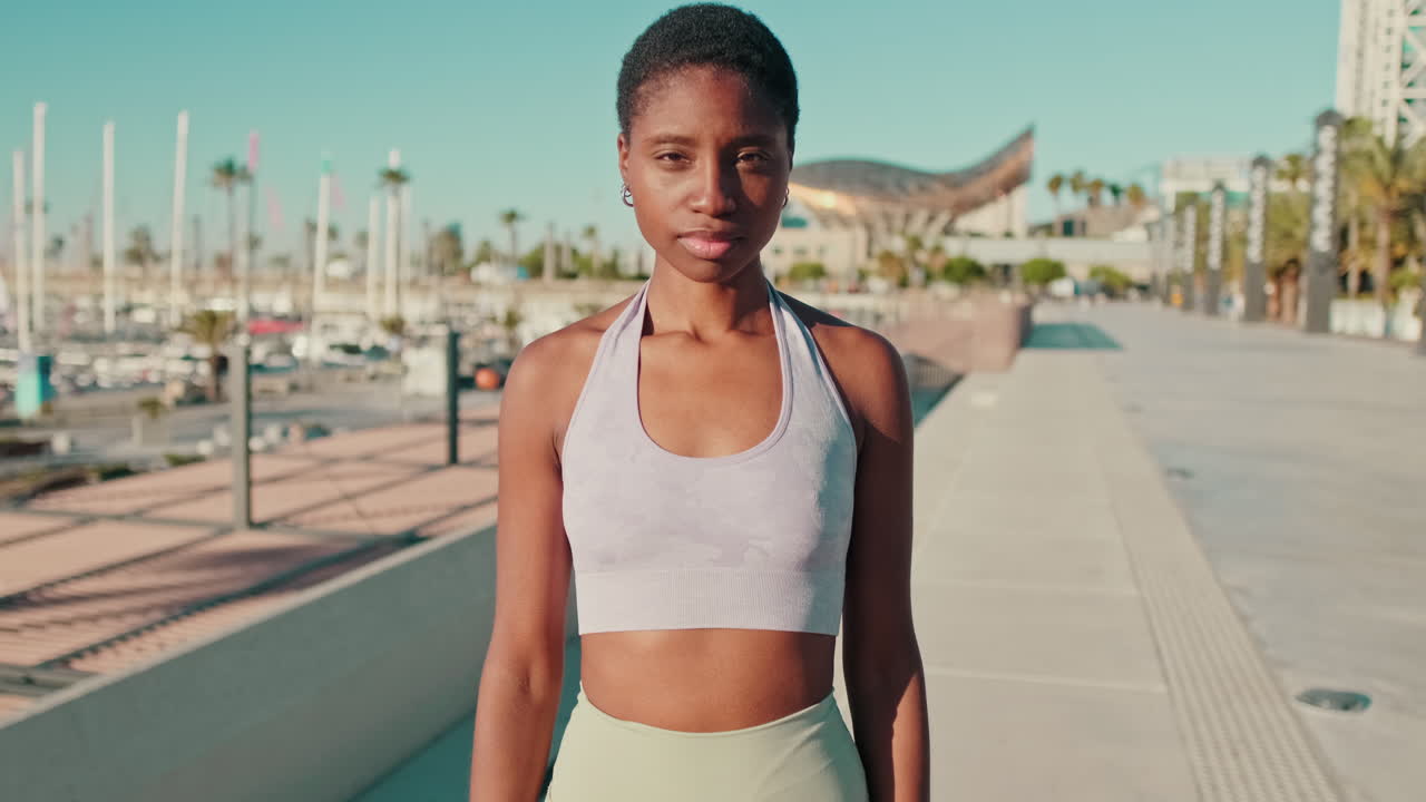 Jovem mulher negra confiante em roupa esportiva em pé na orla.