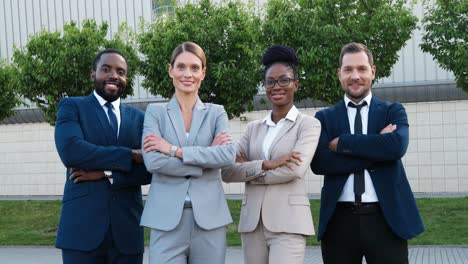 Group-of-multiethnic-business-people-in-stylish-clothes-smiling-and-looking-at-camera-with-arms-crossed-in-the-street