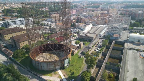drone aéreo inclinado hacia abajo disparado sobre el gasómetro o gasómetro a lo largo de un río en el distrito de ostiense de roma, italia en un brillante día soleado